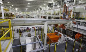 Figure 5. The billet preparation area includes a gas furnace, an induction furnace, and billet quenching system, with an aerial manipulator to move the billets through the stages and to the press.