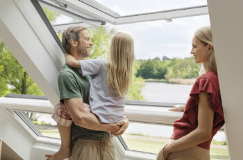 A family stands by an open Velux window.