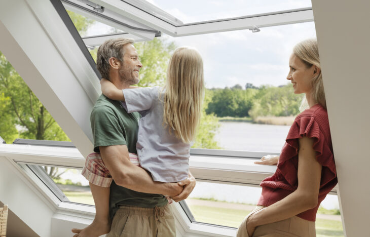 A family stands by an open Velux window.