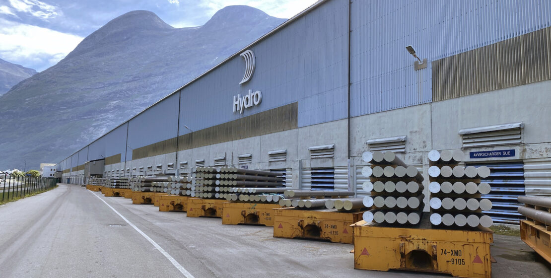 Exterior of Hydro's Sunndal plant, showing aluminum billet stacked in front