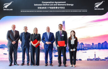 five business persons stand in a row before a promotional poster