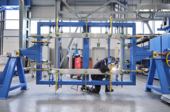 a man welds an aluminum frame for a train car