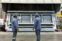 Two men stand in front of a closed aluminum furance.