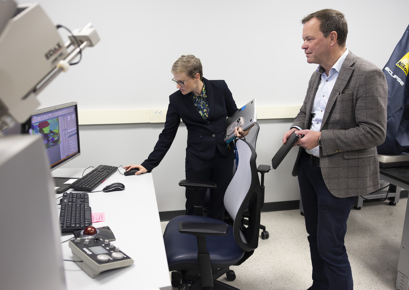 A woman demonstrates research tools to an man in a suit.