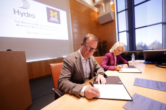 A man and a woman sit at a table signing documents.