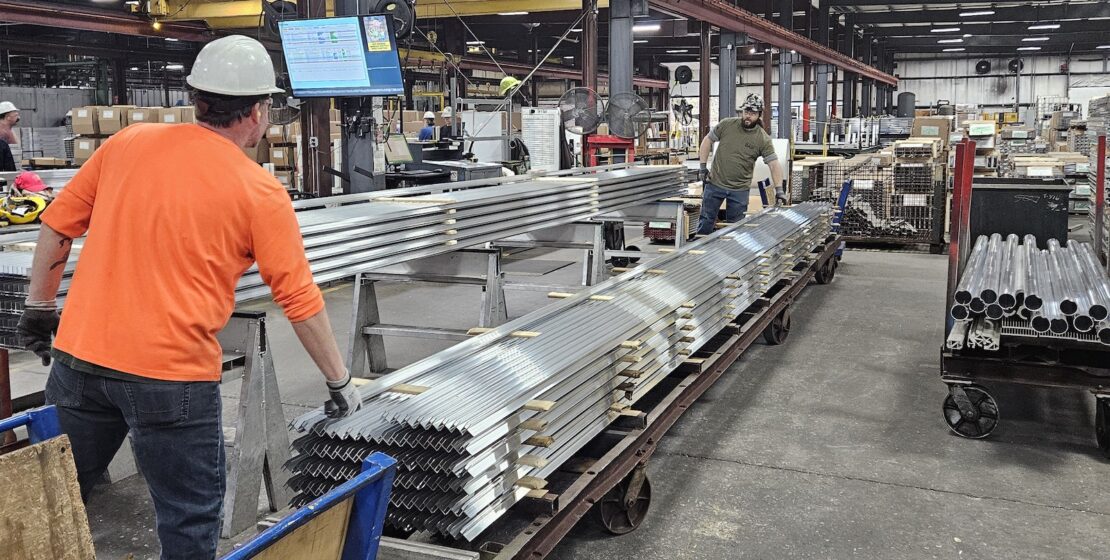 A man adjusts extruded aluminum profiles in an industrial plant.