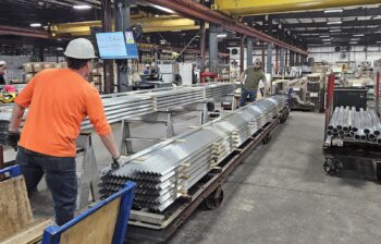 A man adjusts extruded aluminum profiles in an industrial plant.