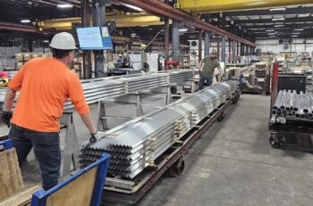 A man adjusts extruded aluminum profiles in an industrial plant.
