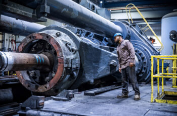 A man peers into the machinery of a piece of industrial equipment.
