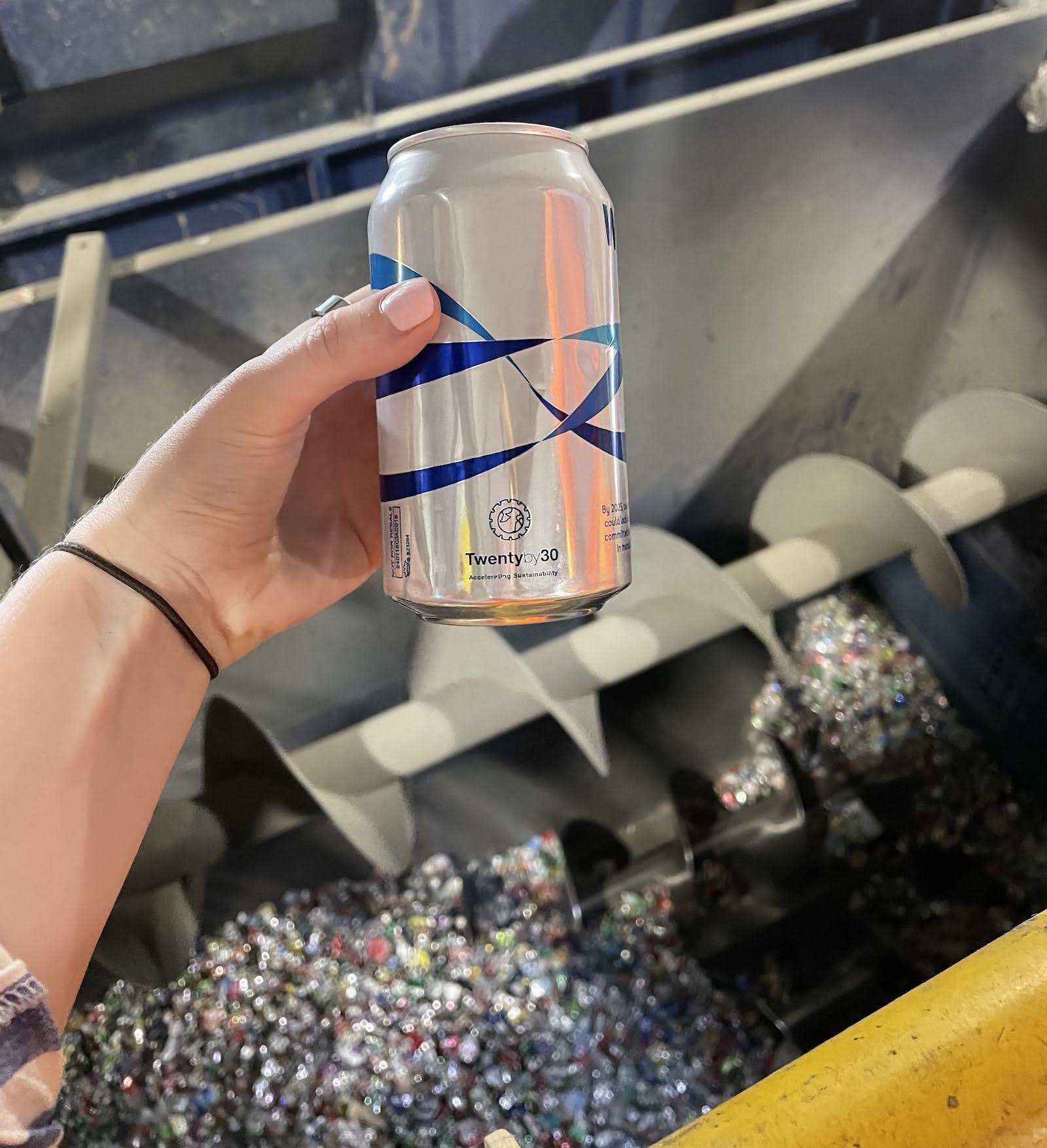A hand holds up a can overtop of an eddy current machine for sorting scrap.