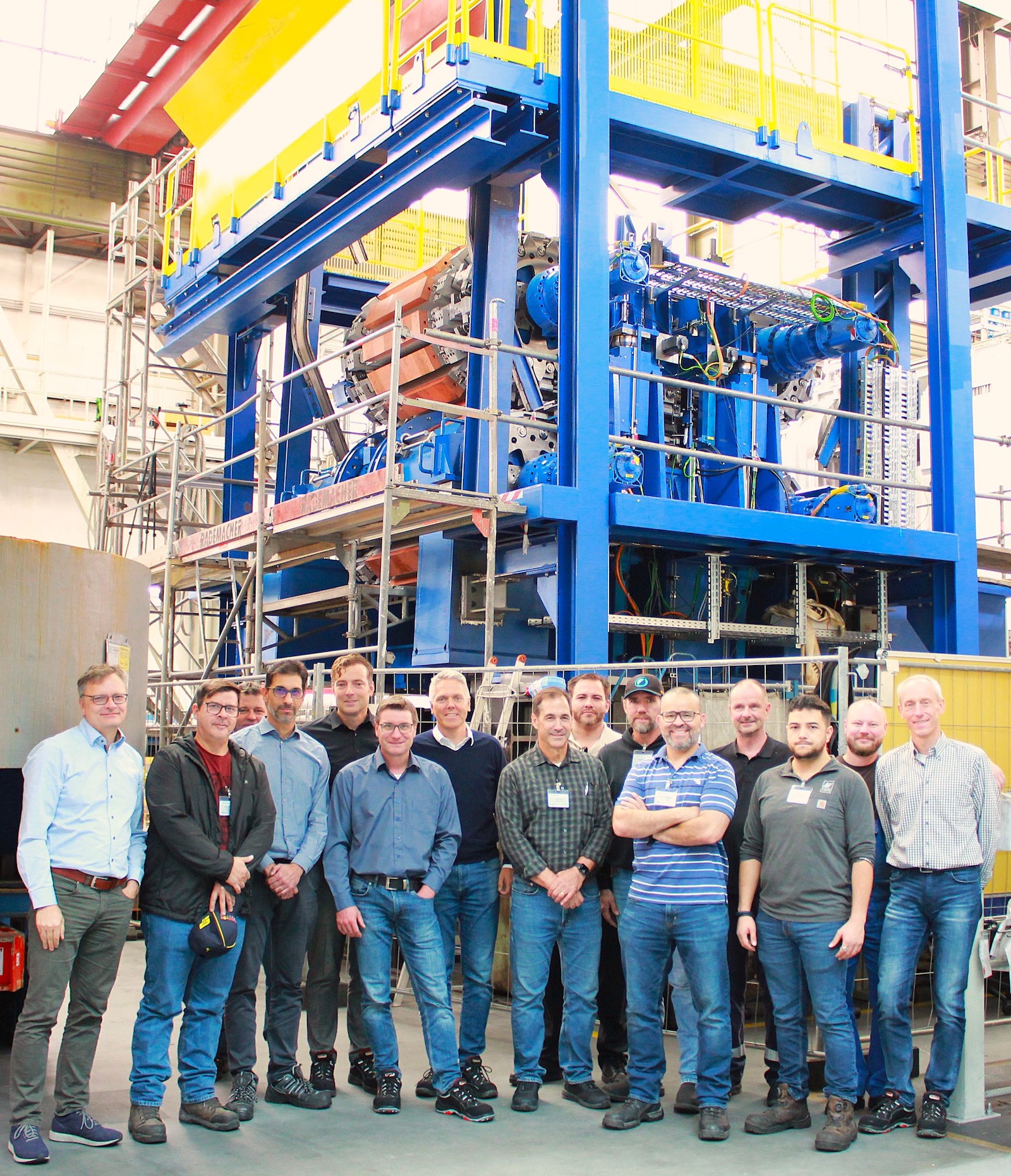 A group of people stand before a continuous casting machine