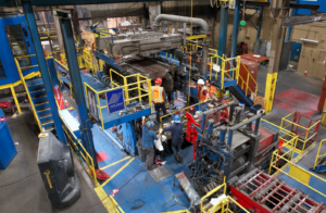 Several men stand on the continuous casting machine as part of the installation process.
