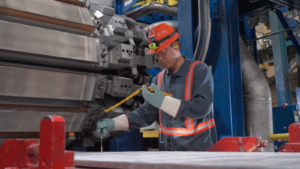 A man uses a tool to check the quality of aluminum strip coming out of the continuous casting machine.