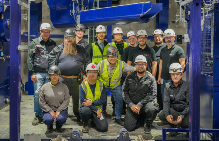 A group of engineers stand next to industrial equipment
