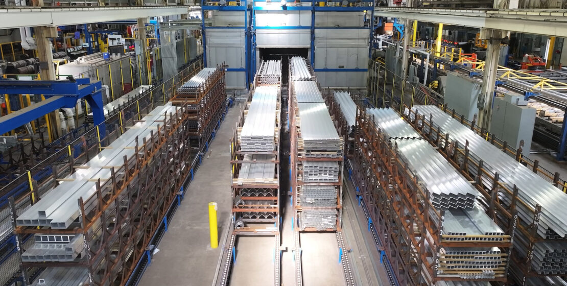 Aluminum extrusions in bundles prepared for aging in the furnaces in the background.
