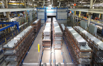 Aluminum extrusions in bundles prepared for aging in the furnaces in the background.