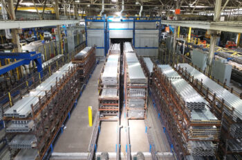 Aluminum extrusions in bundles prepared for aging in the furnaces in the background.