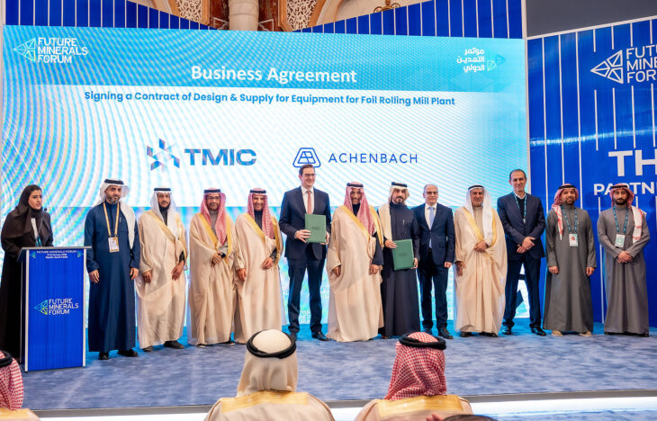 A group of people in suits and middle easter dress stand on stage for an announcement ceremony