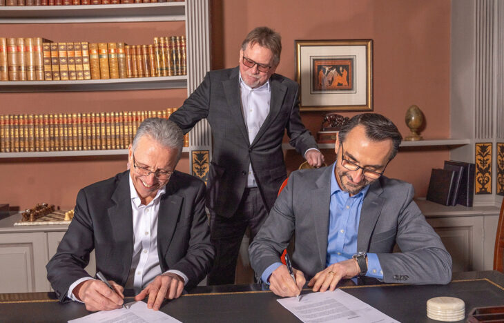 Three men in suits sign a contract