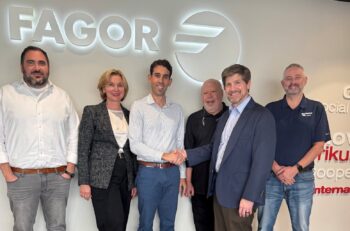 Six people in casual business attire stand in front of a sign that reads, Fagor.