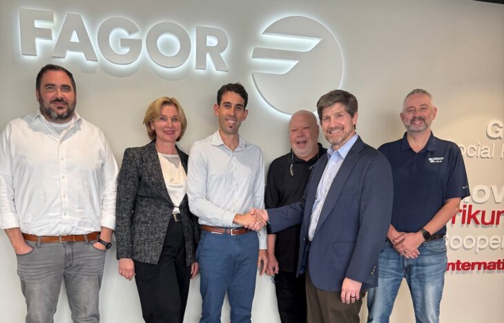 Six people in casual business attire stand in front of a sign that reads, Fagor.