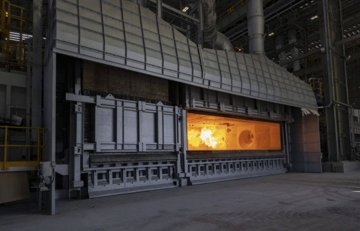 An industrial furnace, with an open door showing orange flames inside.