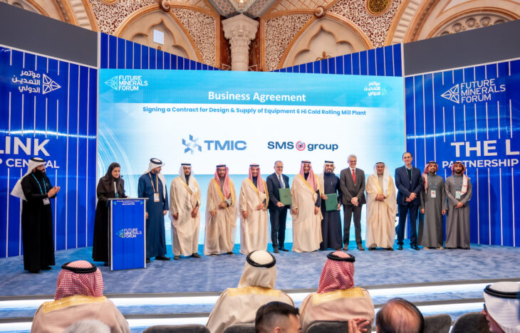 A group of people in suits and middle easter dress stand on stage for an announcement ceremony