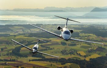 Two aircraft flying over green fields.