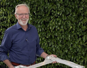 A man in a blue shirt holding an aluminum profile