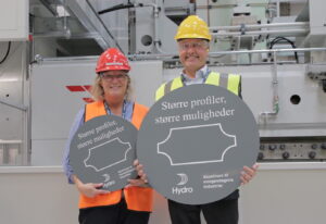 Two people in hard hats, holding grey signs.