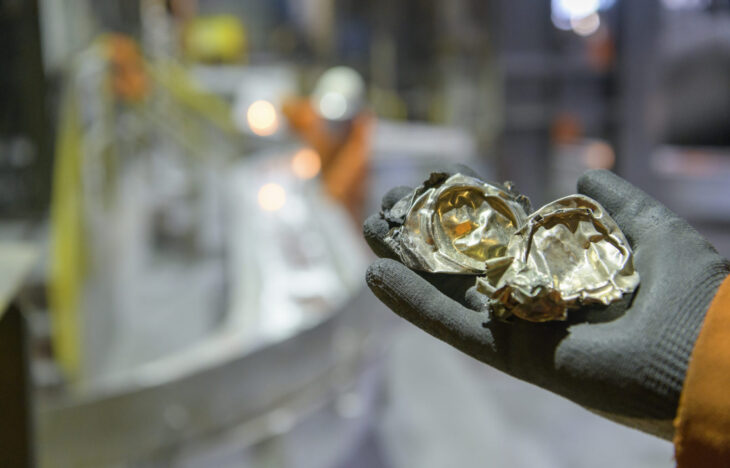 A hand holds up crushed aluminum cans