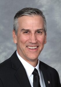 Headshot of a white man in a suit