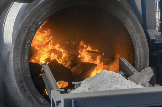 Rotary recycling furnace showing the flames melting aluminum scrap.