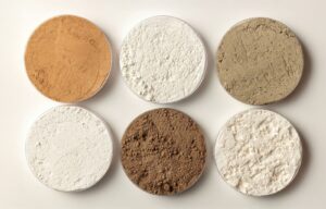 Photo of six pots of rare earth oxides in varying shades of powders.
