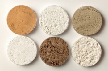 Photo of six pots of rare earth oxides in varying shades of powders.