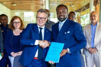 Two men shake hands holding a contract.
