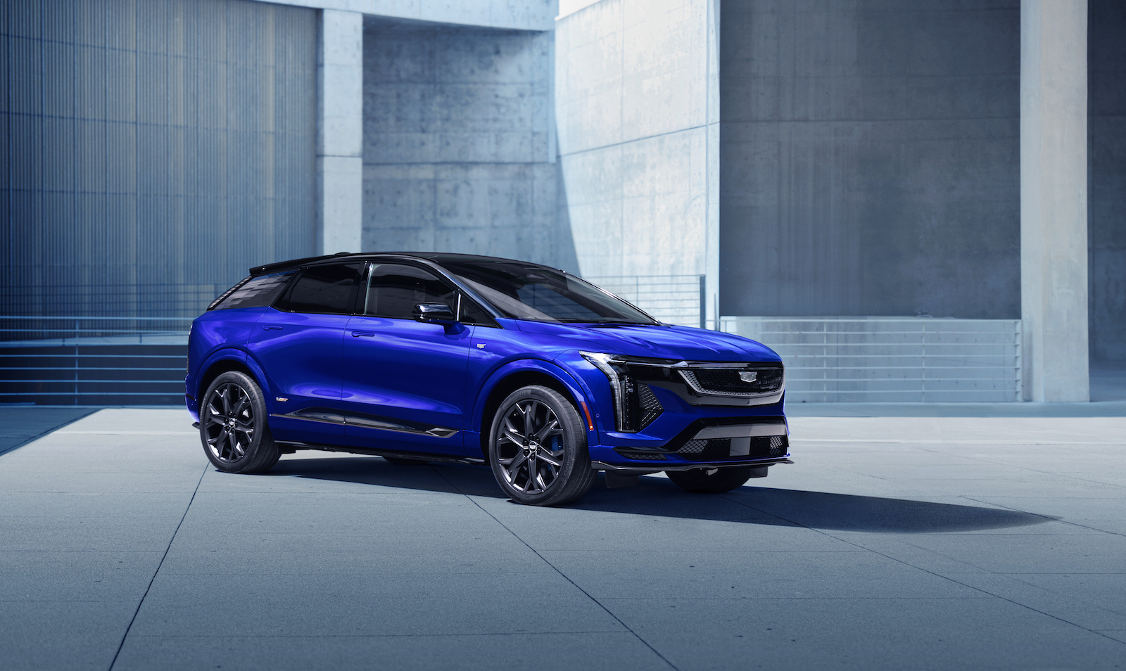 A bright blue SUV against the grey of a cement building.