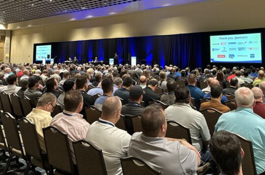 A roomful of people watching a presentation